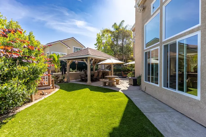 Outdoor living space home addition with a gazebo, patio and lush lawn by Teknik