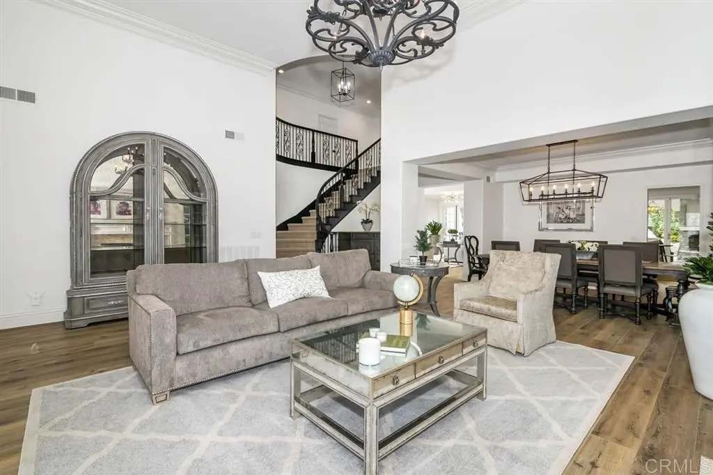 Elegant living and dining area with hardwood flooring, plush seating — remodel in Encinitas