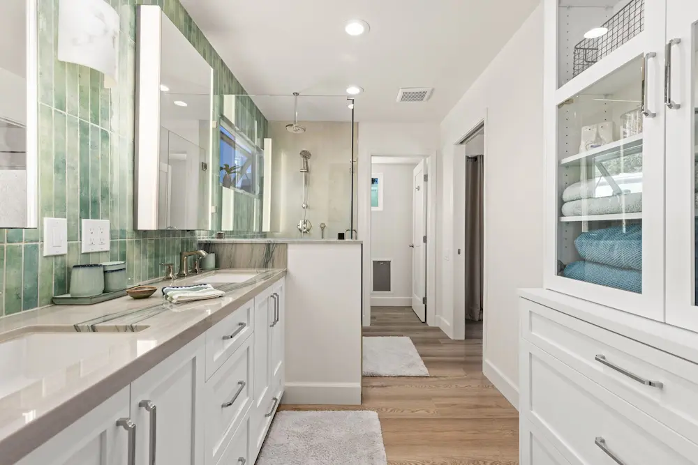 Bathroom remodel with green tile backsplash, white vanity and glass shower enclosure
