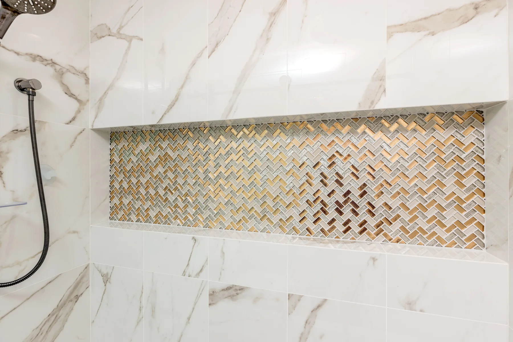 Detailed marble shower wall with a herringbone mosaic niche by Teknik Design & Remodeling