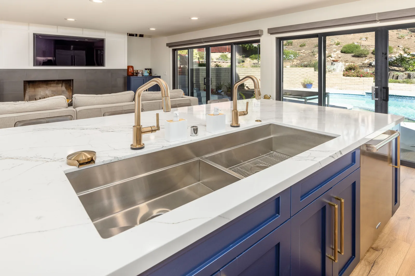 Waterfall marble kitchen island with brass faucet and pool view, De Luca remodel