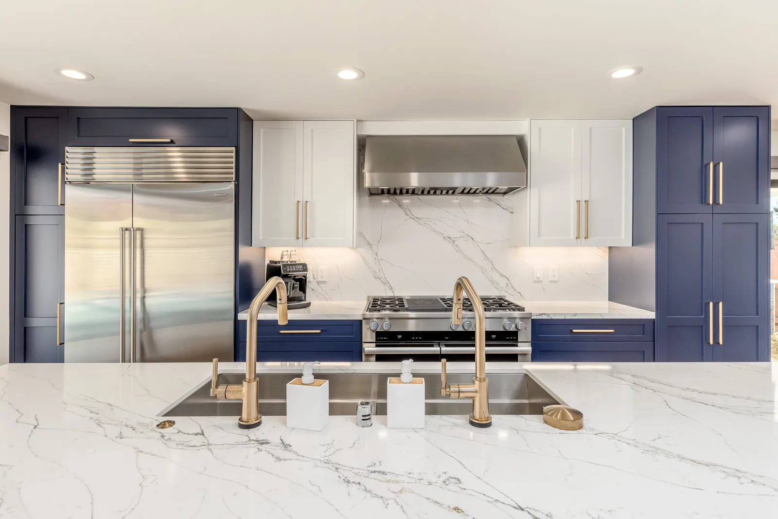 Navy and white marble chef kitchen with brass fixtures after De Luca whole-home remodel in Rancho Peñasquitos