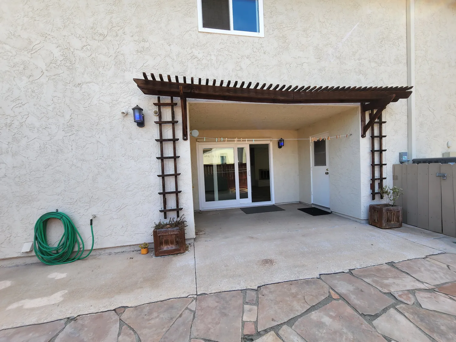 Bare concrete backyard with empty pergola frame before the De Luca remodel