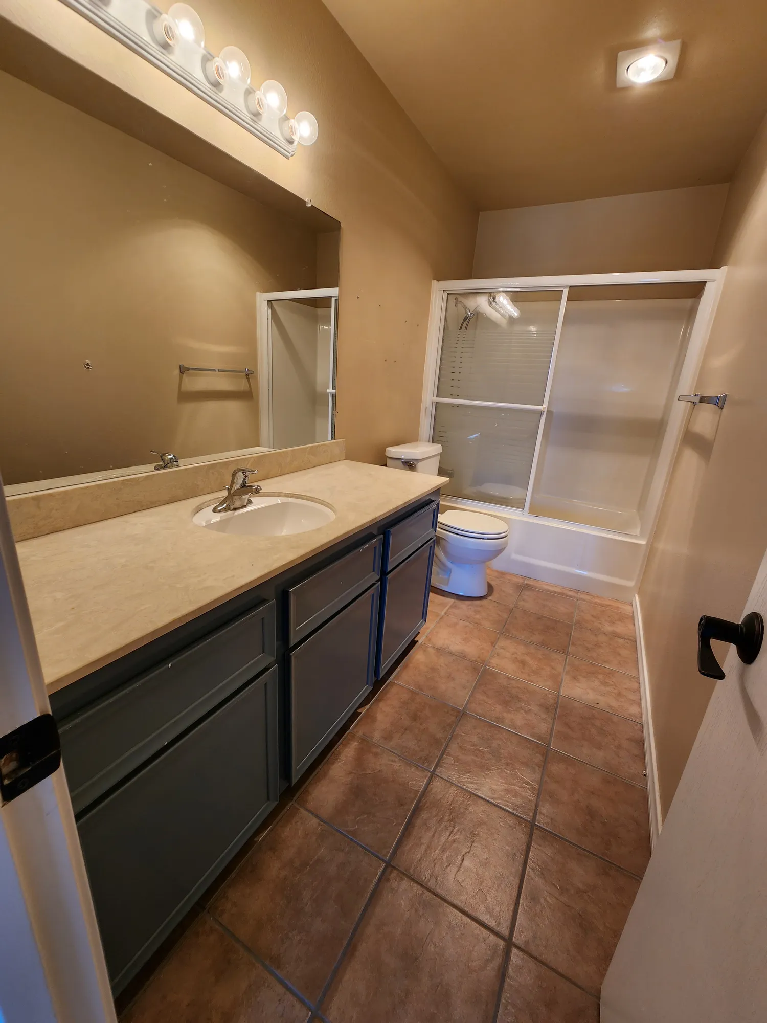 Dated bathroom with brown tile and black countertop before the De Luca remodel