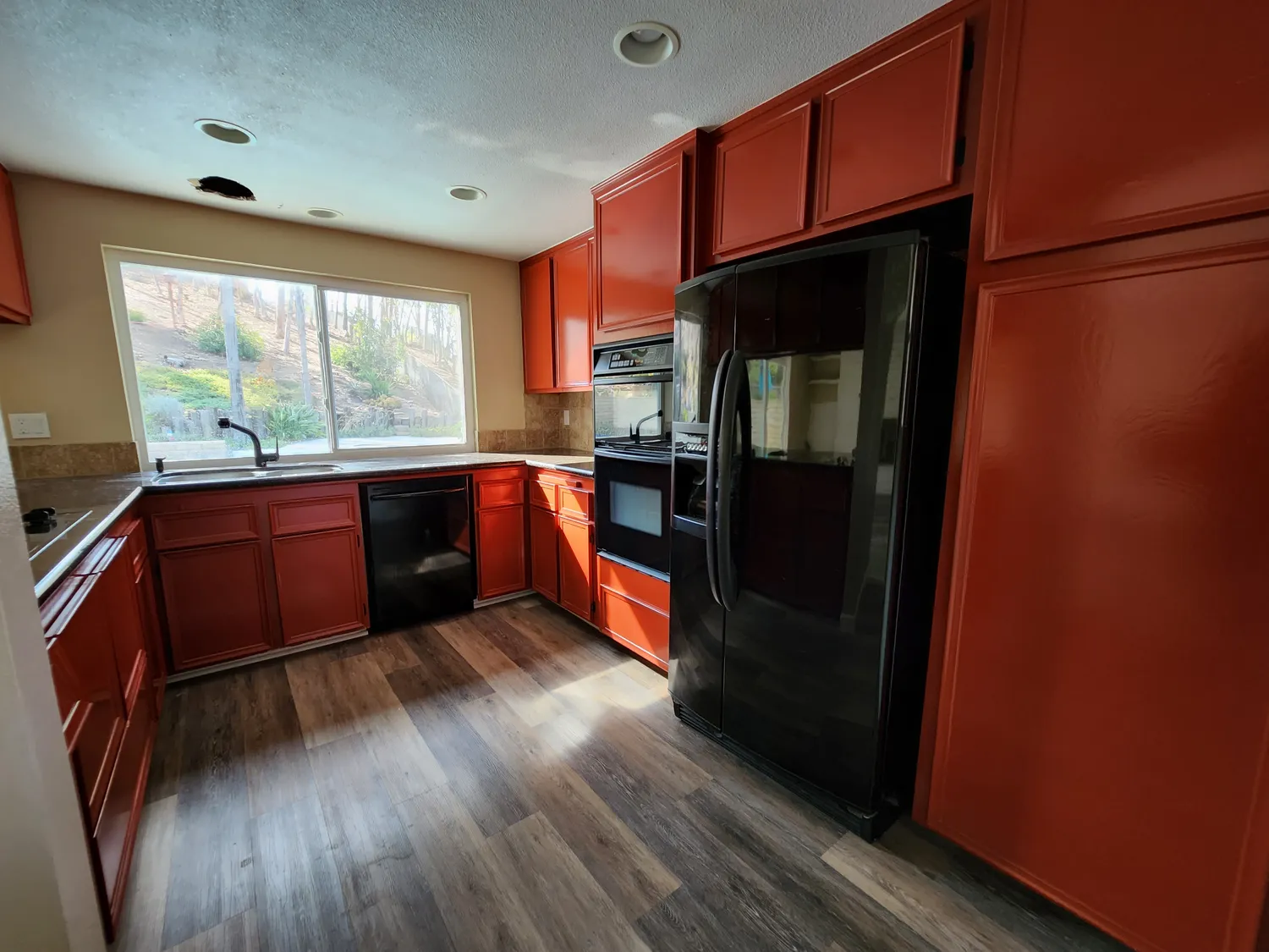 Dated red-cabinet kitchen with dark appliances before the Scripps Ranch remodel
